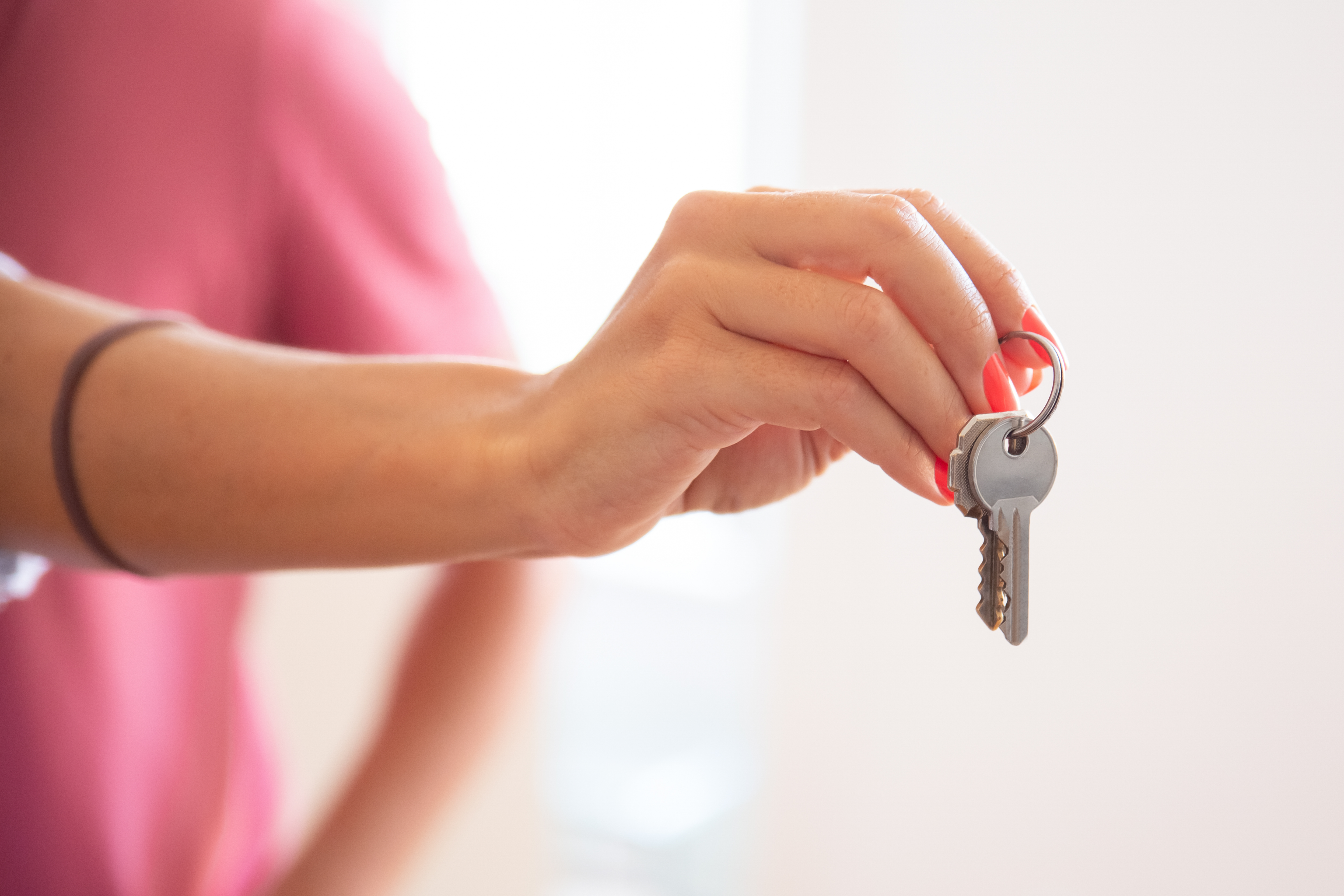Illustration of choosing an enterprise CMS: a hand holds a key on a key ring against a blurred pink background